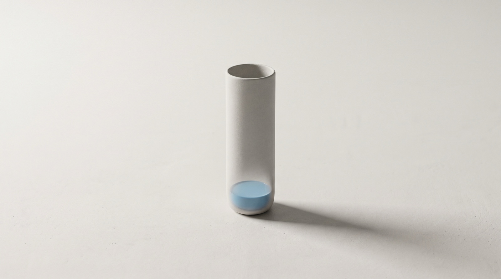 A tall slender pale-grey vessel standing alone on a calm off-white surface, filled only a little at the very bottom with still sky-blue liquid, like a day's energy running low long before the day is done.