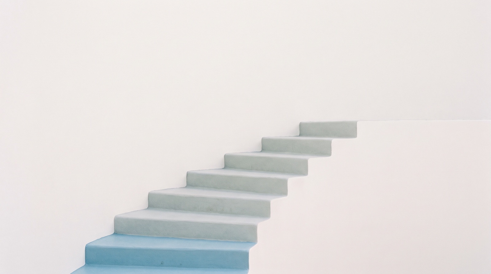 A gentle flight of shallow pale steps rising across a calm off-white surface, the lowest step in sky-blue, like a small first move in a long climb.