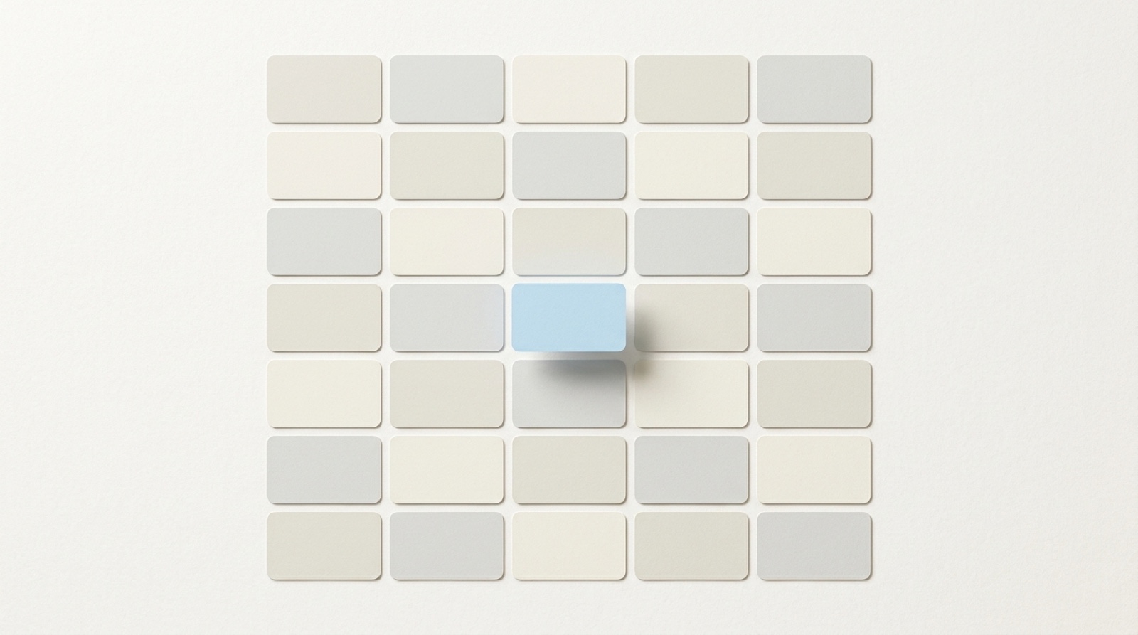 A calm grid of small blank paper cards with one sky-blue card gently lifted above the rest.