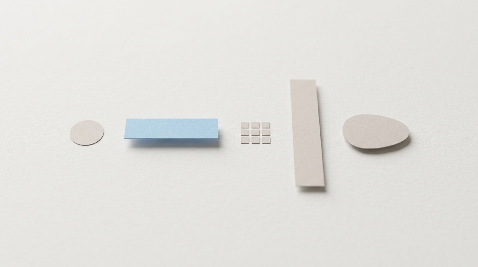 Five plain paper shapes of different forms laid out in a row on off-white paper, one of them a soft sky-blue bar.