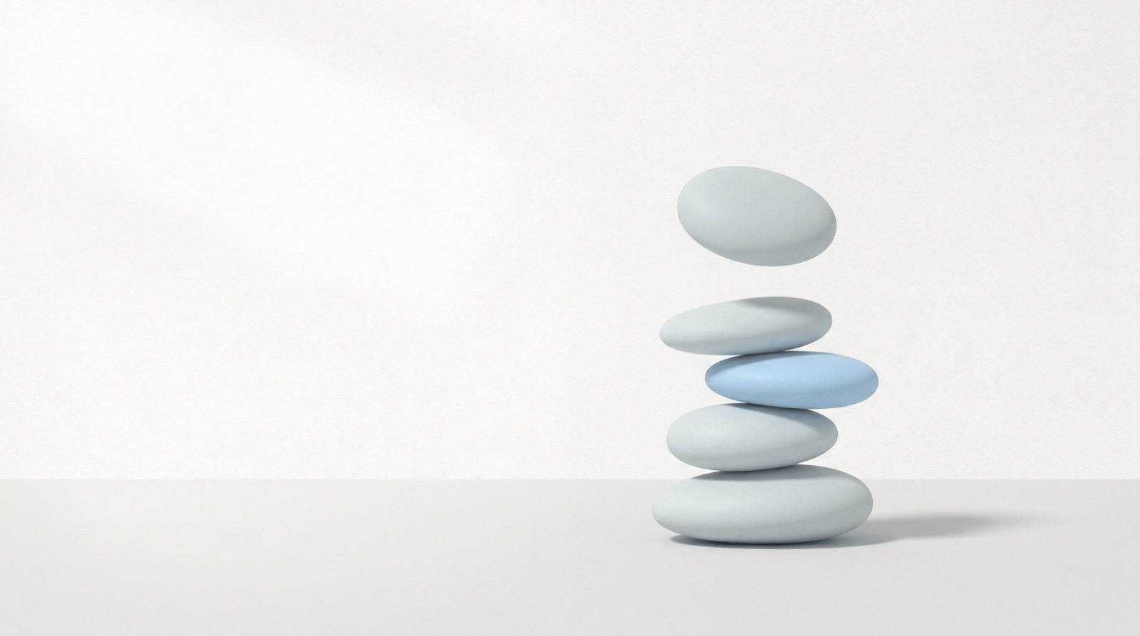 A neat vertical stack of smooth rounded forms in pale grey on a clean surface, the top one lifting away weightlessly, with a single sky-blue form among them, suggesting a heavy load being set down.