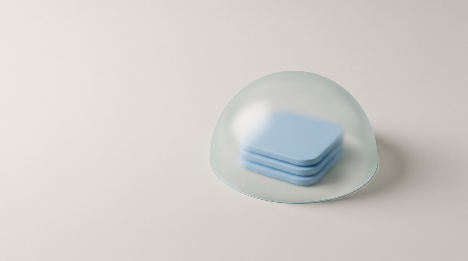 A small stack of soft sky-blue tiles resting under a frosted glass dome on a clean off-white surface.